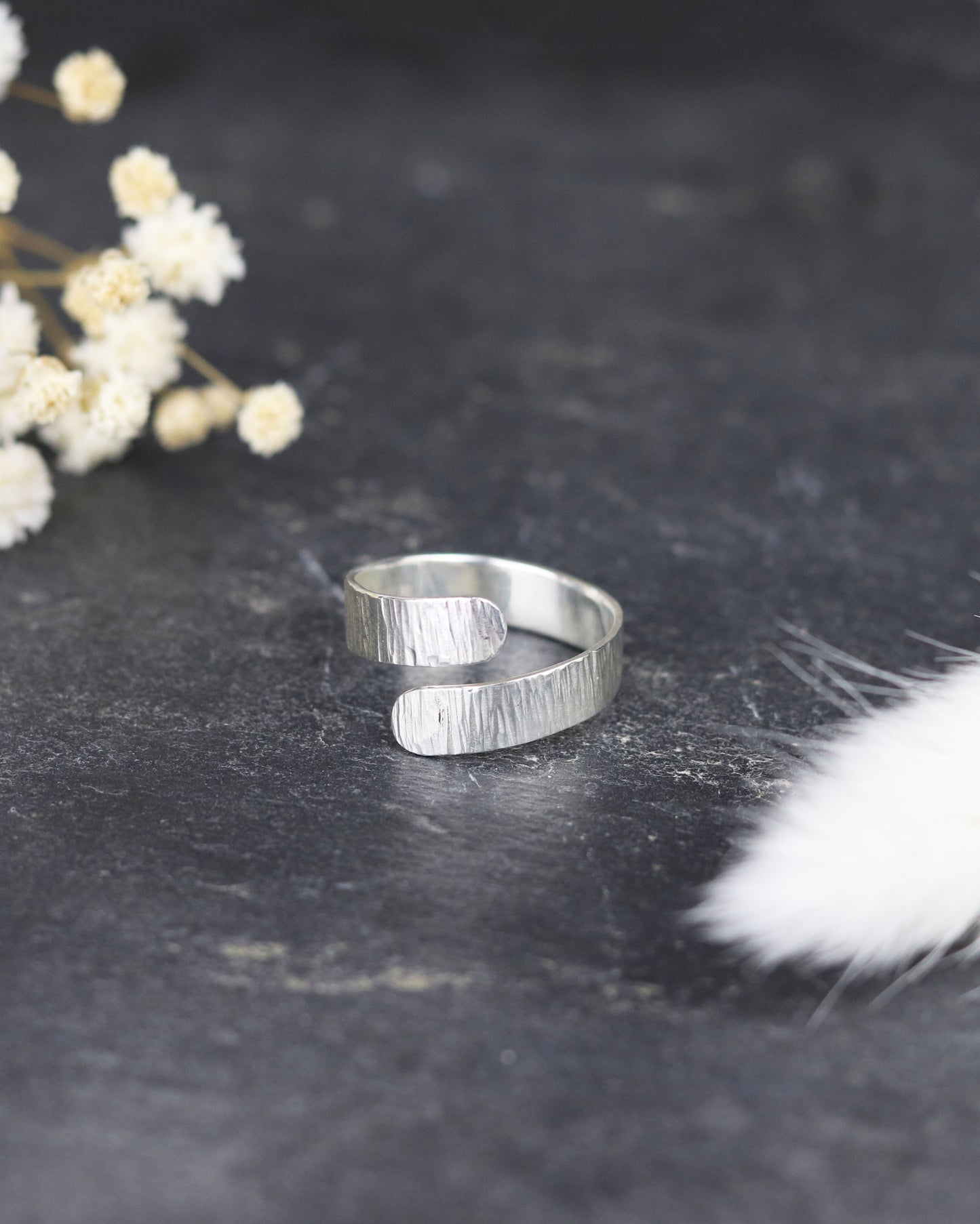 Bague Marion Chappaz réglable Ruban Twist en argent finition ciselée posée sur fond ardoise