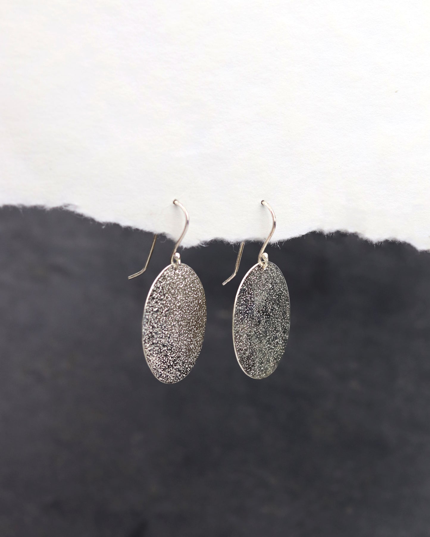 bijoux marion chappaz en argent 925 boucles d'oreilles texturées dormeuses ovales pendantes Emery pour femme sur papier blanc