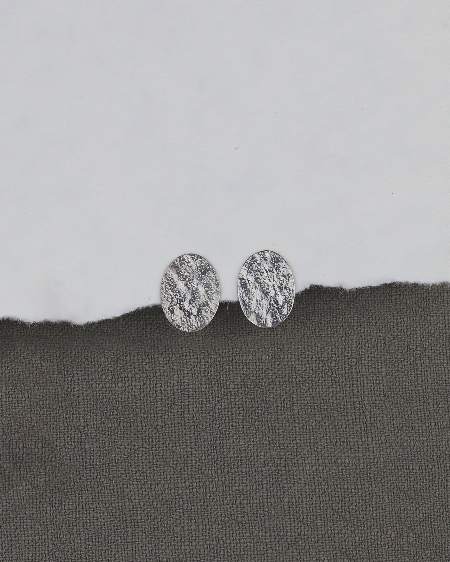 bijoux marion chappaz en argent 925 boucles d'oreilles Emery texturées puces fermoir poussoir papillon tirette belge sur papier blanc et fond tissu kaki pour femme