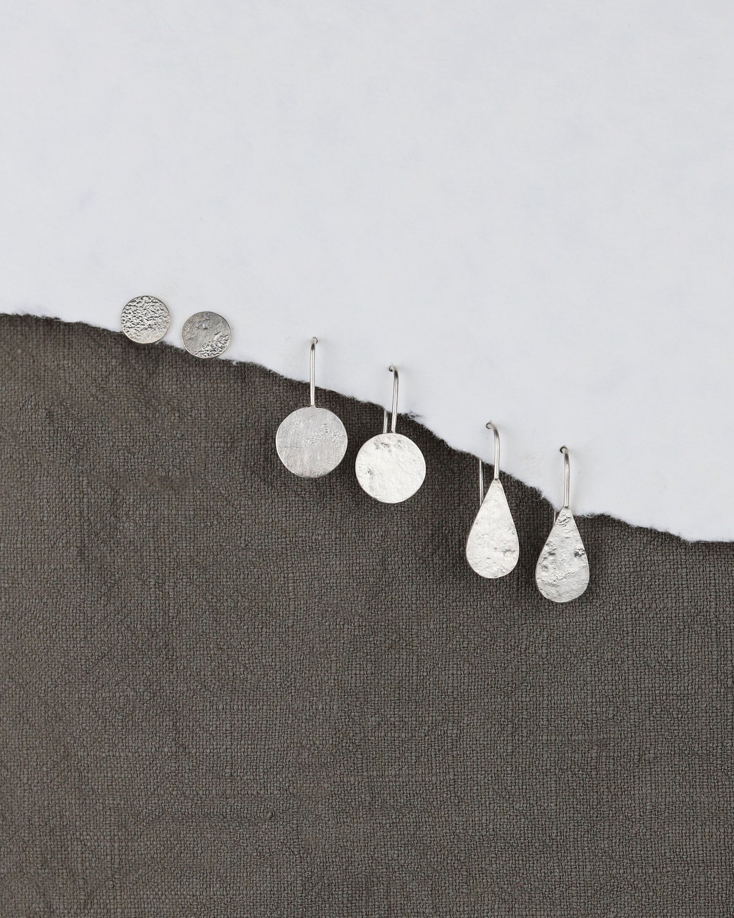 bijoux marion chappaz en argent 925 boucles d'oreilles dormeuses pendantes courtes Moondrop goute texturées lune collection Moon sur papier blanc et tissus kaki