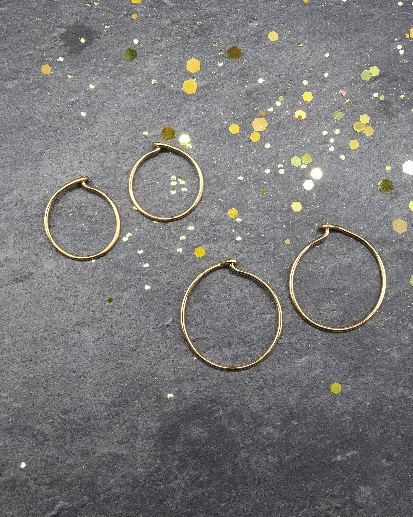 Boucles d'oreilles Créoles en or jaune 750 millièmes lisses fines S et M posées sur une ardoise naturelle