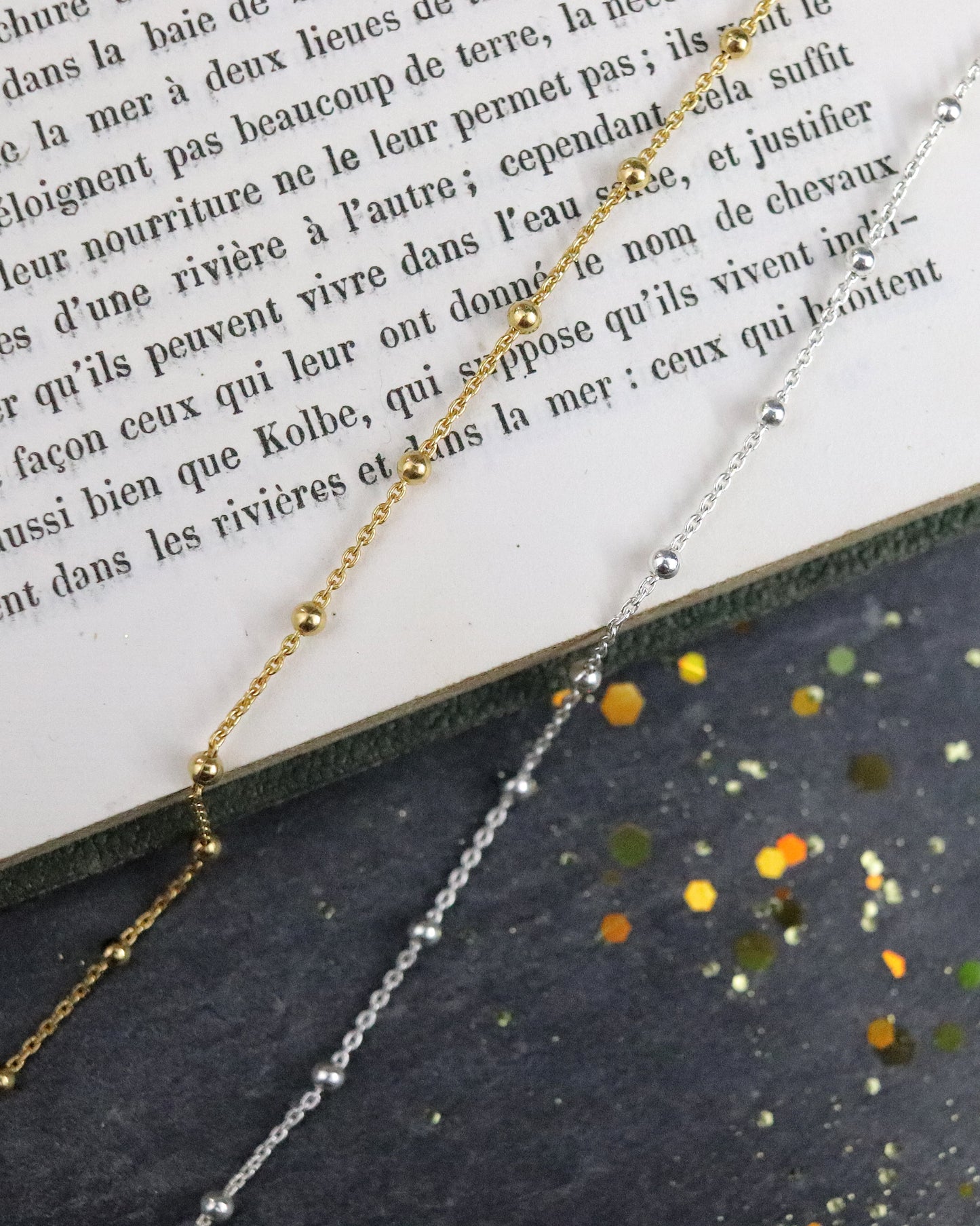 Bracelets Chaine boules en argent 925/1000 et vermeil posés sur un livre et sur une ardoise naturelle