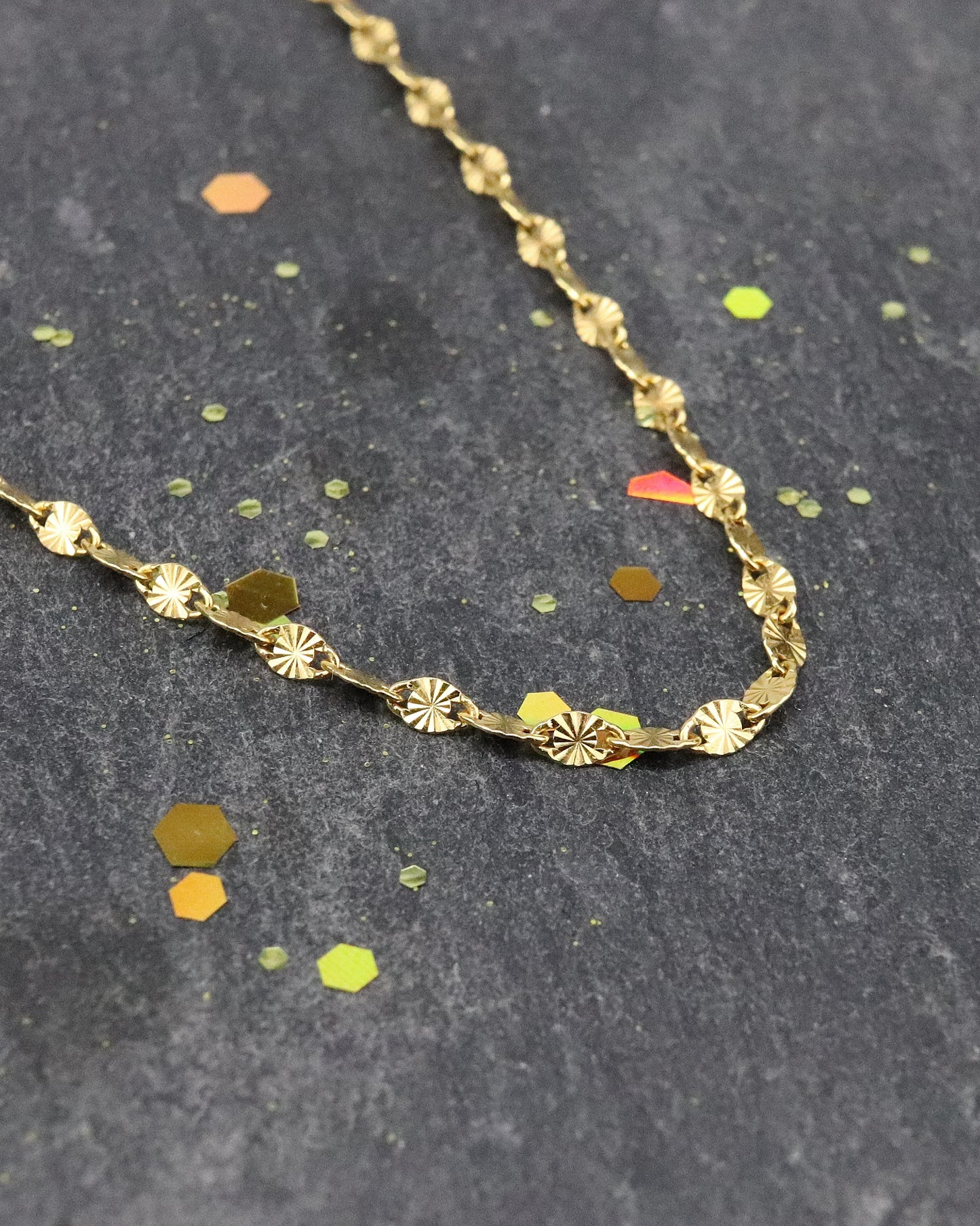 Chaine soleil vermeil zoom sur la maille, posée sur une ardoise naturelle