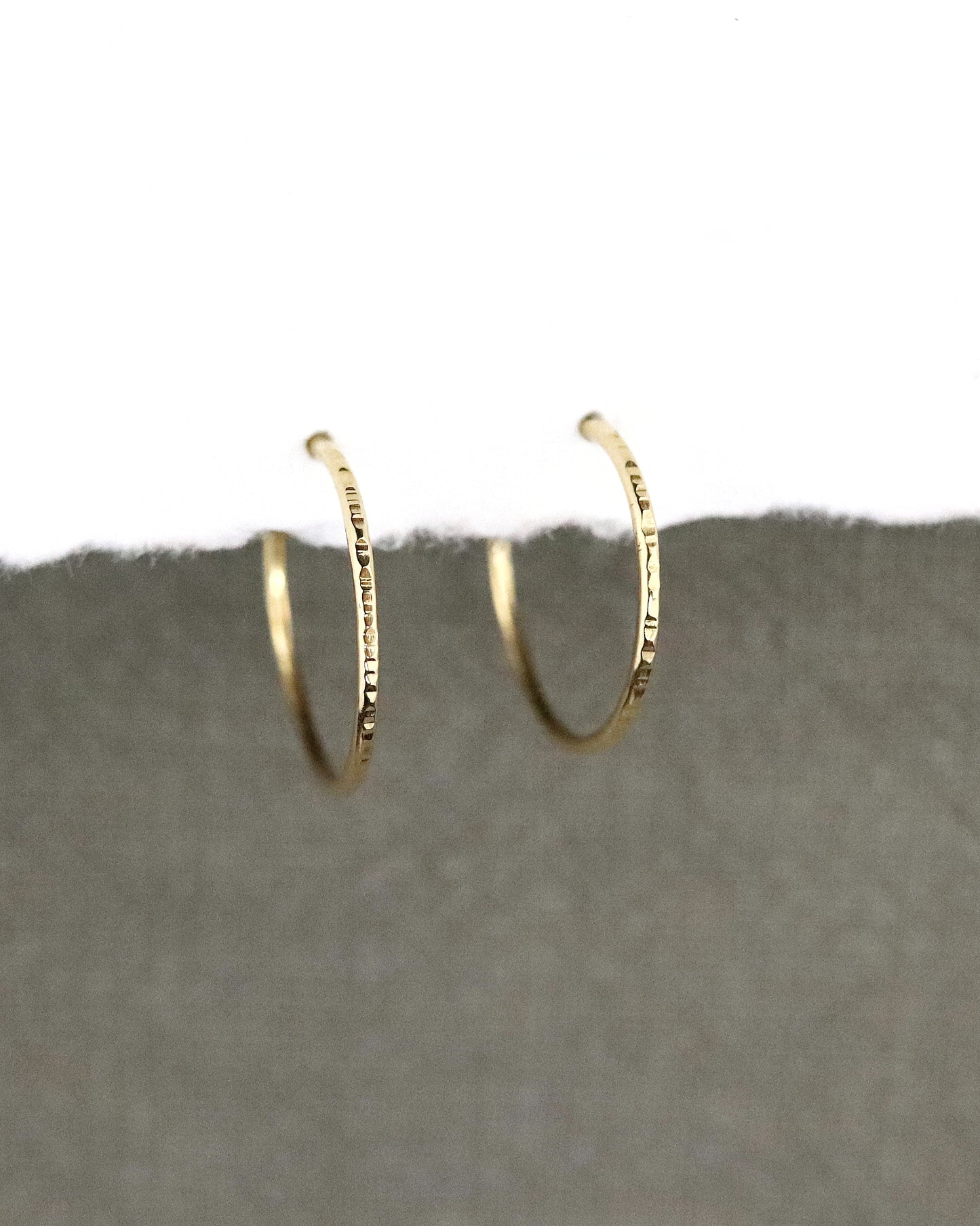 Créoles fines Boucles d'oreilles en or 750/1000 ciselées sur papier blanc et fond tissus kaki 18k