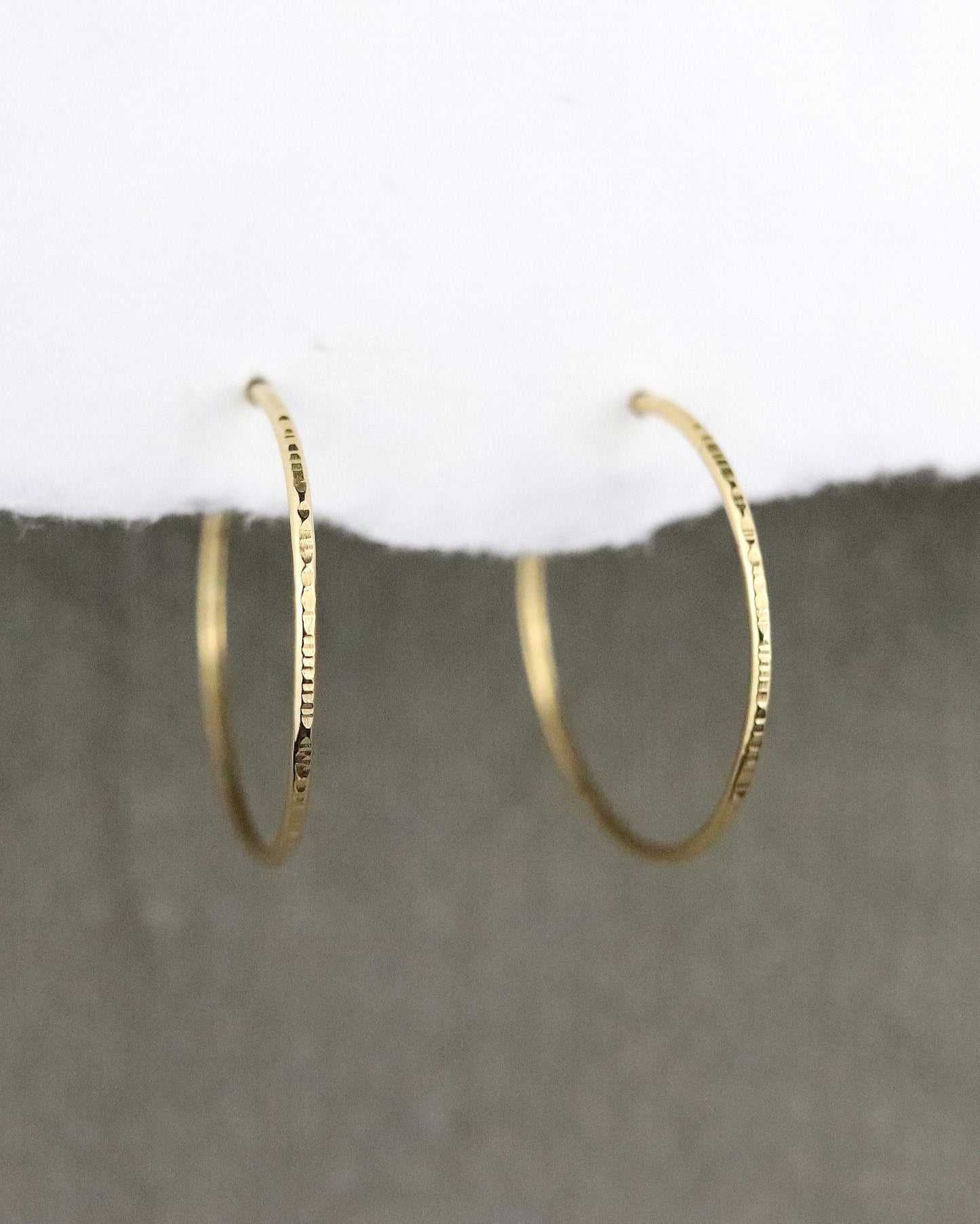 boules d'oreilles créoles fines en vermeil (argent 925/1000 plaqué or 5 microns)taille M ciselées sur papier blanc et fond tissu kaki