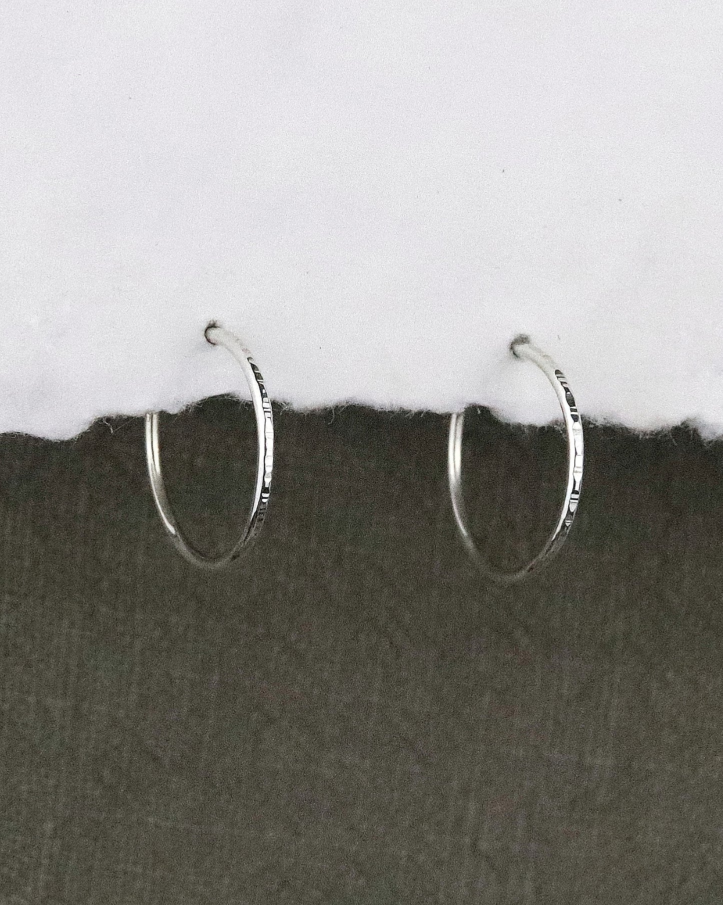 boules d'oreilles créoles fines en argent 925/1000 taille S ciselées sur papier blanc et fond tissu kaki