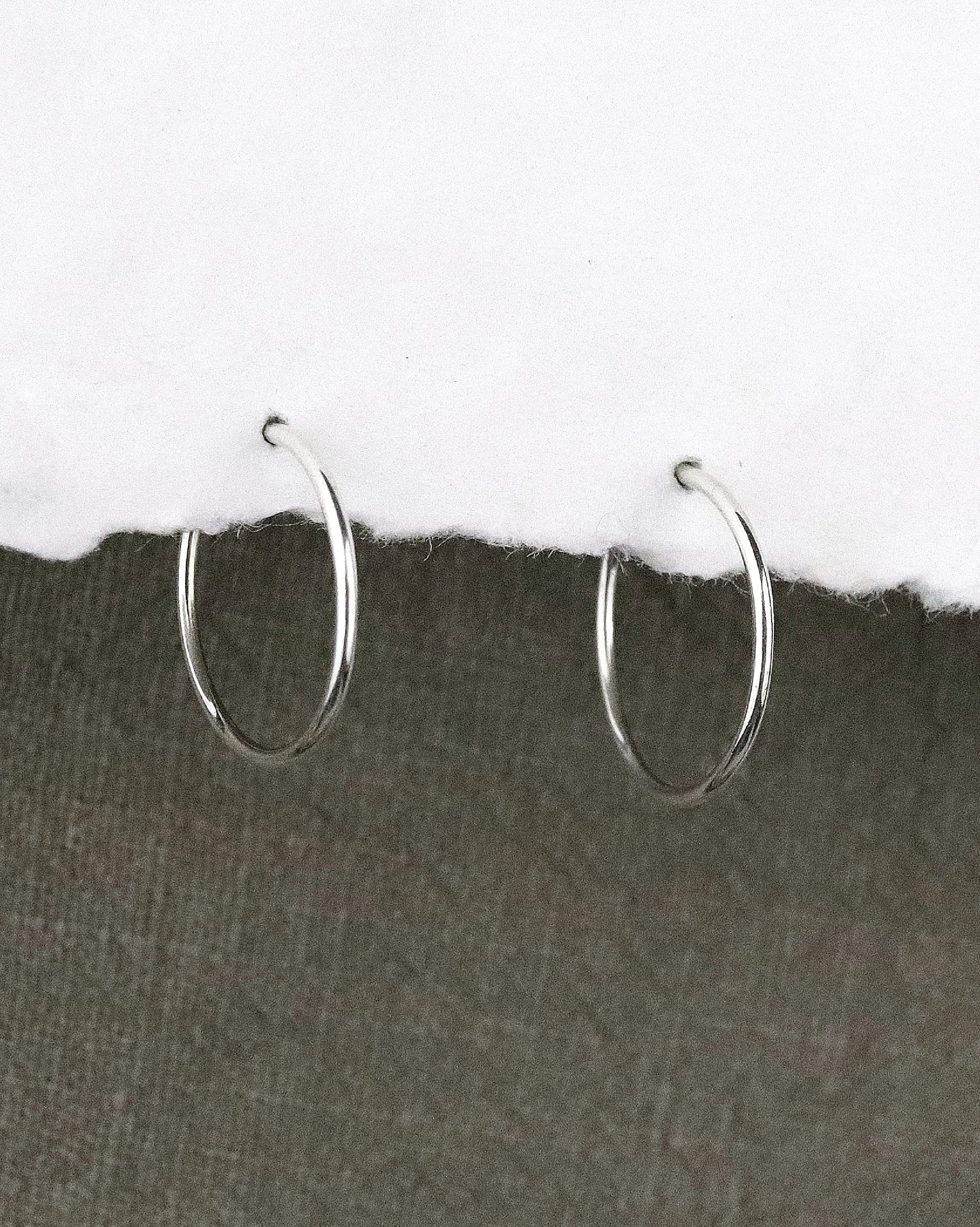 boules d'oreilles créoles fines en argent 925/1000 taille S lisses sur papier blanc et fond tissu kaki