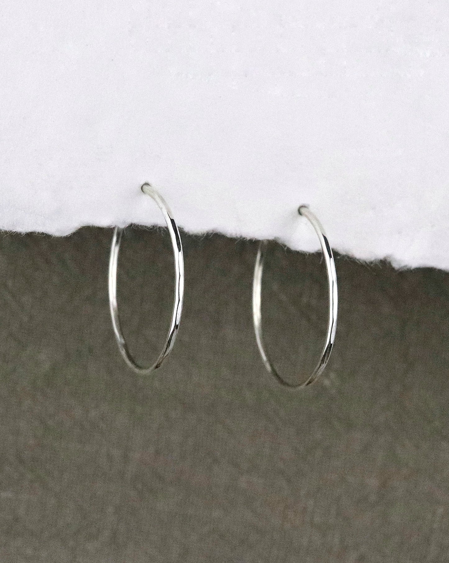boules d'oreilles créoles fines en argent 925/1000 taille M martelées sur papier blanc et fond tissu kaki