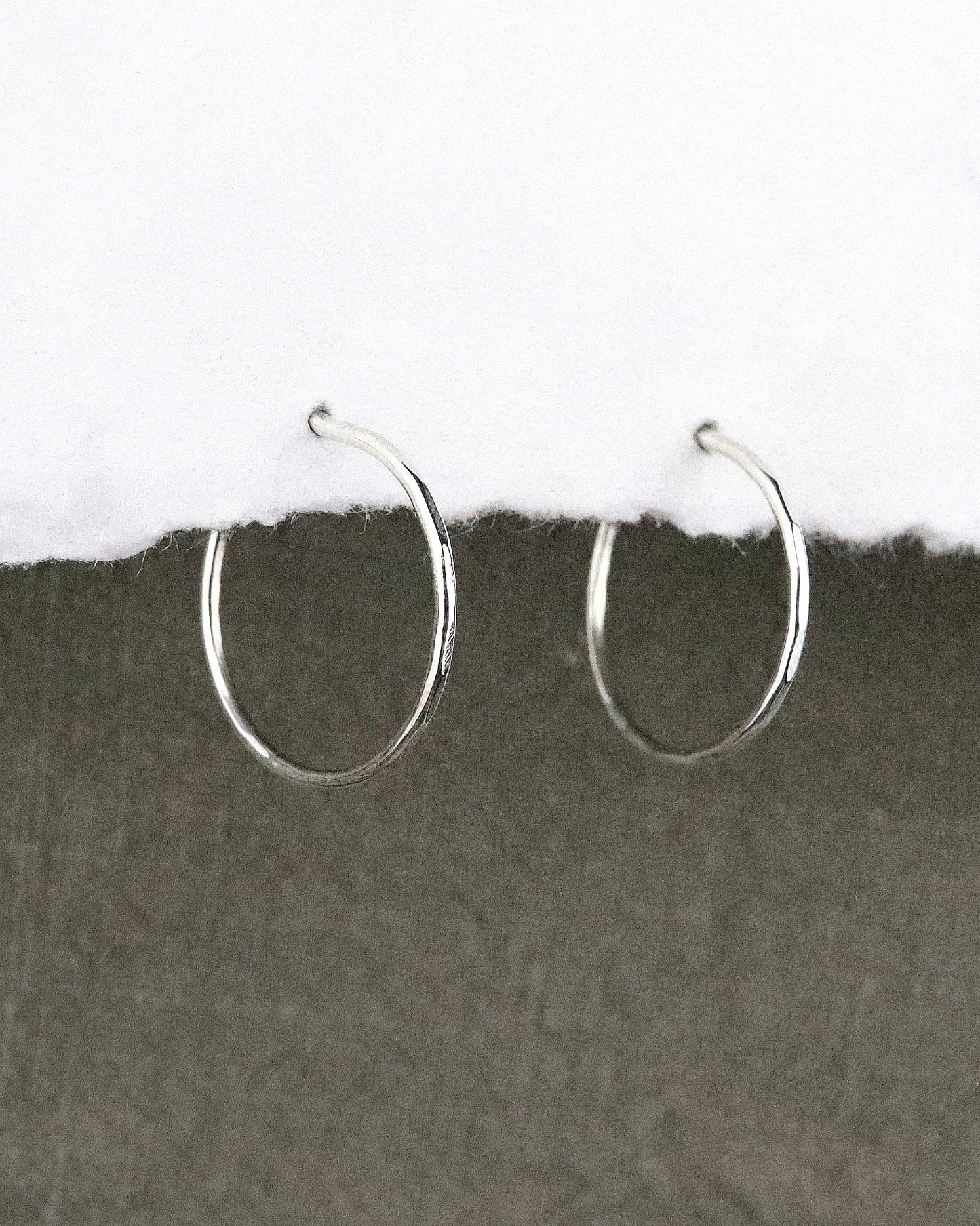 boules d'oreilles créoles fines en argent 925/1000 taille S ciselées sur papier blanc et fond tissu kaki