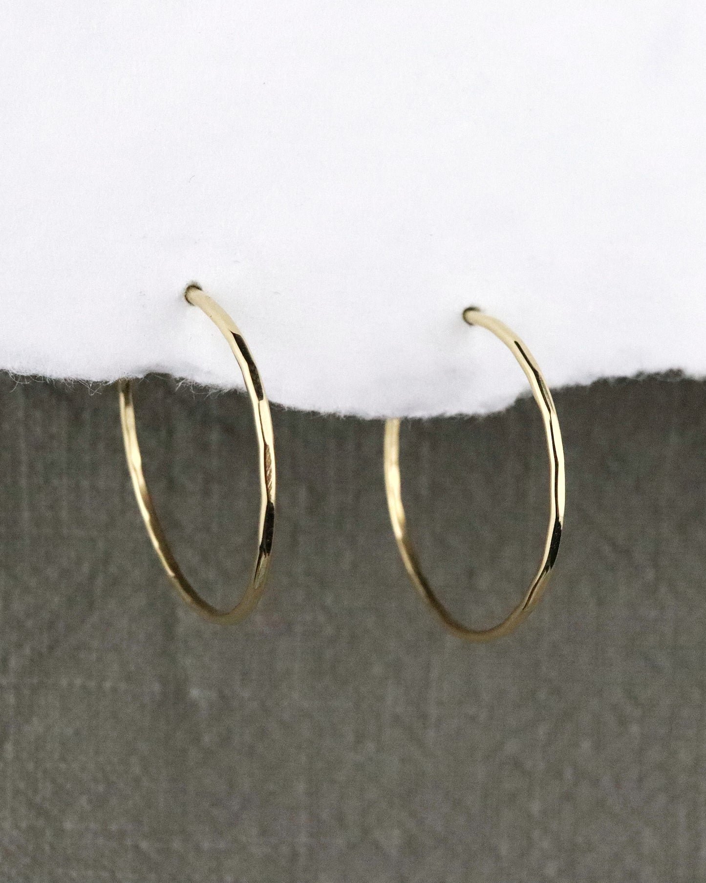 boules d'oreilles créoles fines en vermeil (argent 925/1000 plaqué or 5 microns)taille M martelées sur papier blanc et fond tissu kaki