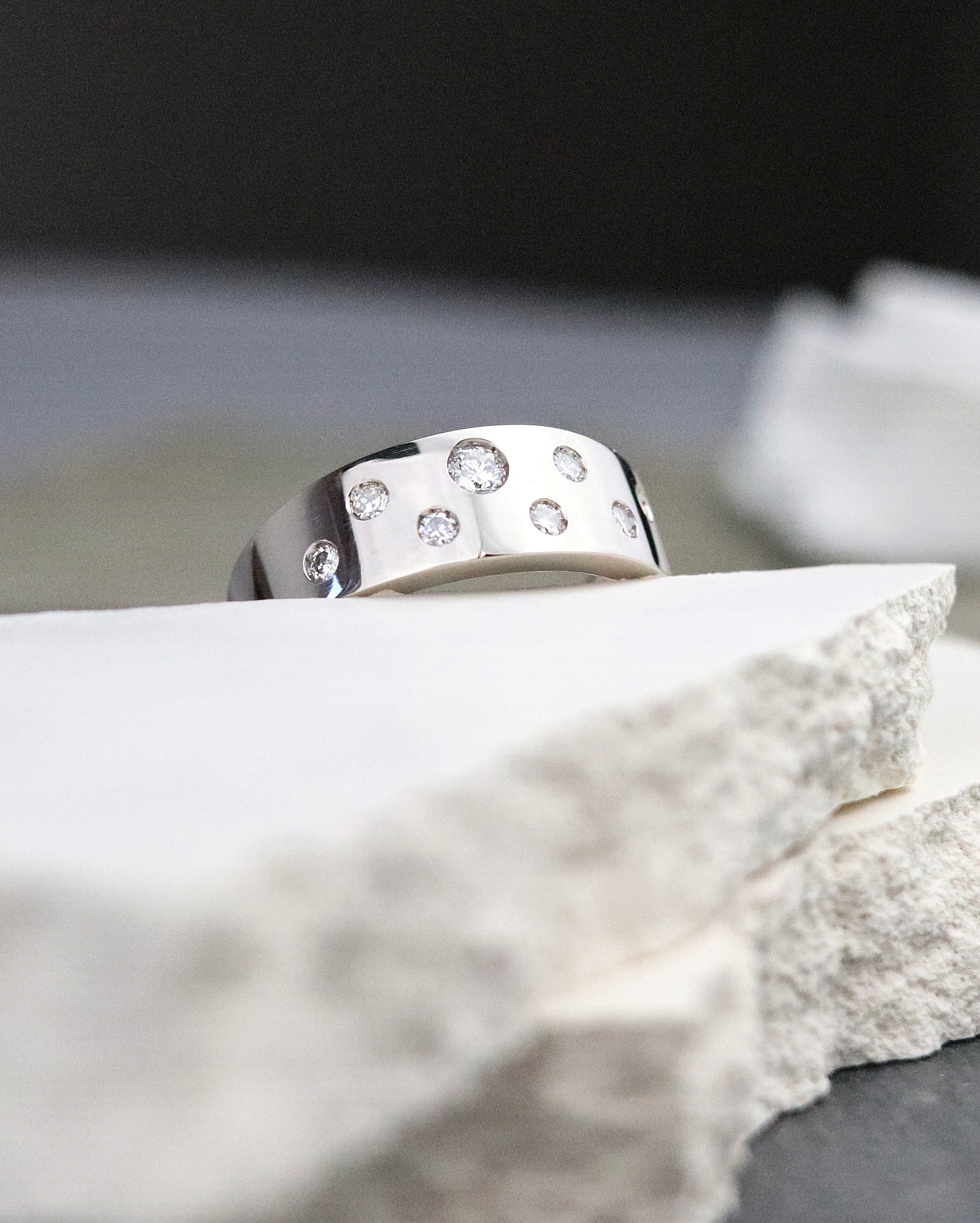 Bague en or gris palladié sertie de 8 diamants posée sur une pierre blanche bijou sur mesure
