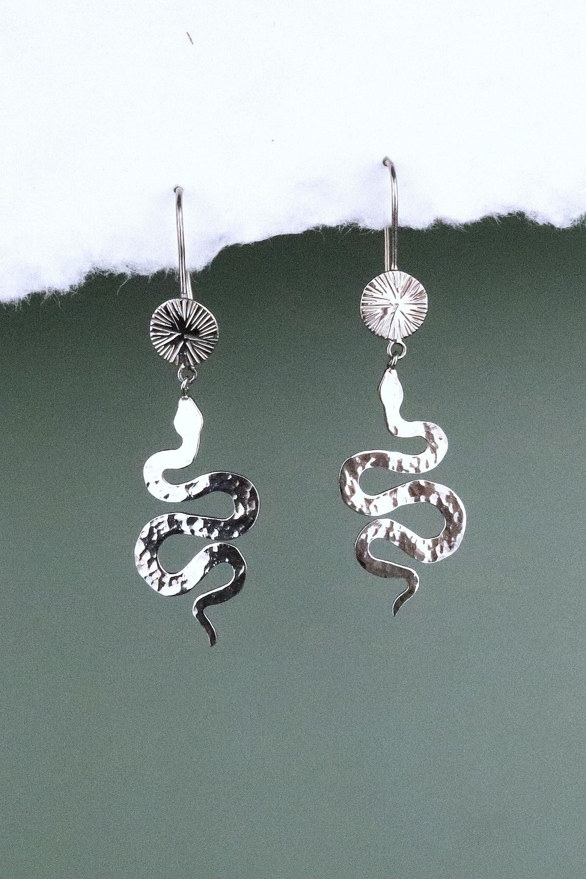 Bijoux Marion Chappaz boucles d'oreilles dormeuses serpent et soleil en argent 925/1000 suspendues sur fond blanc et vert