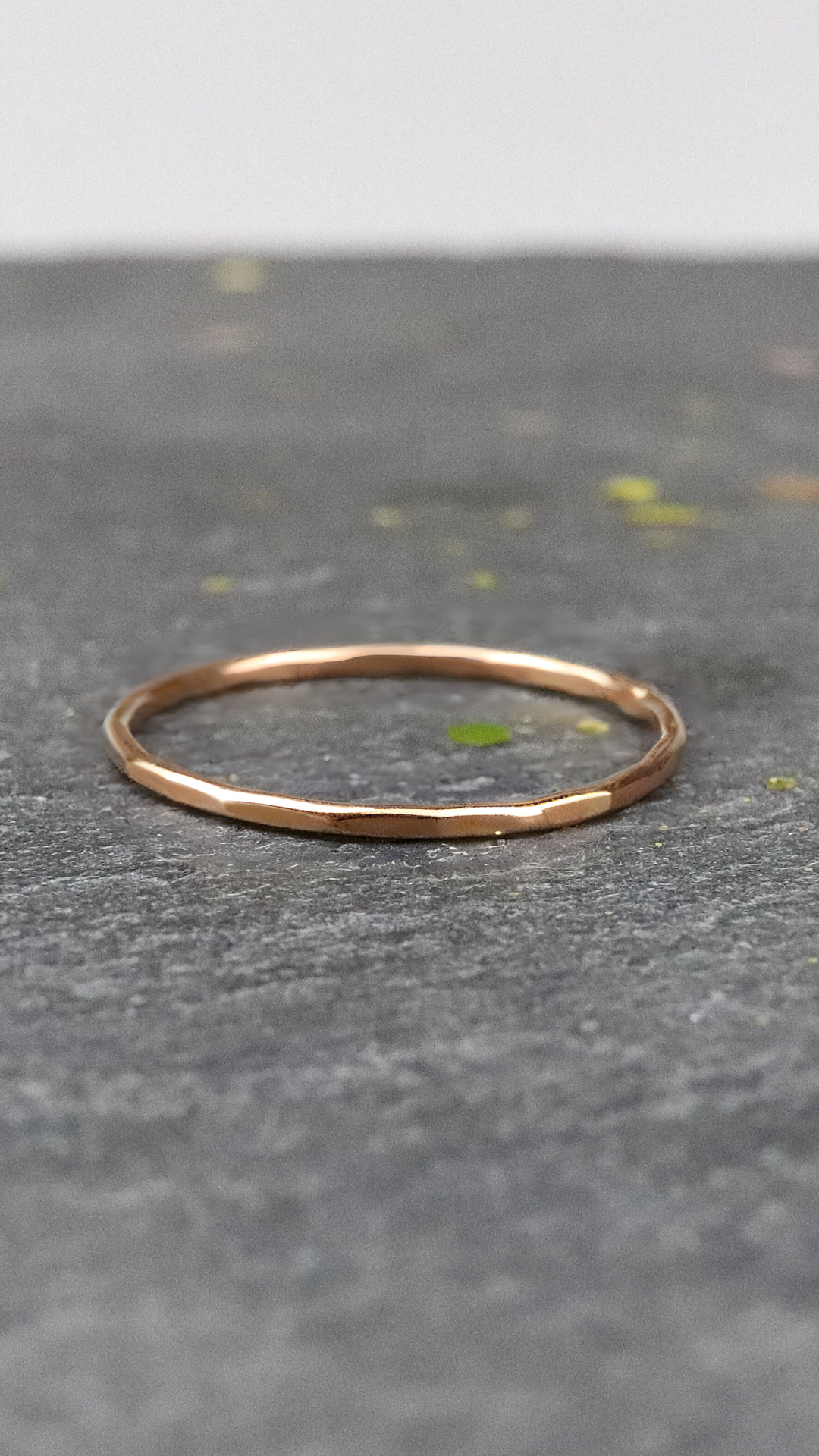 Bague fine or rose 750/1000 martelée posée sur une ardoise naturelle