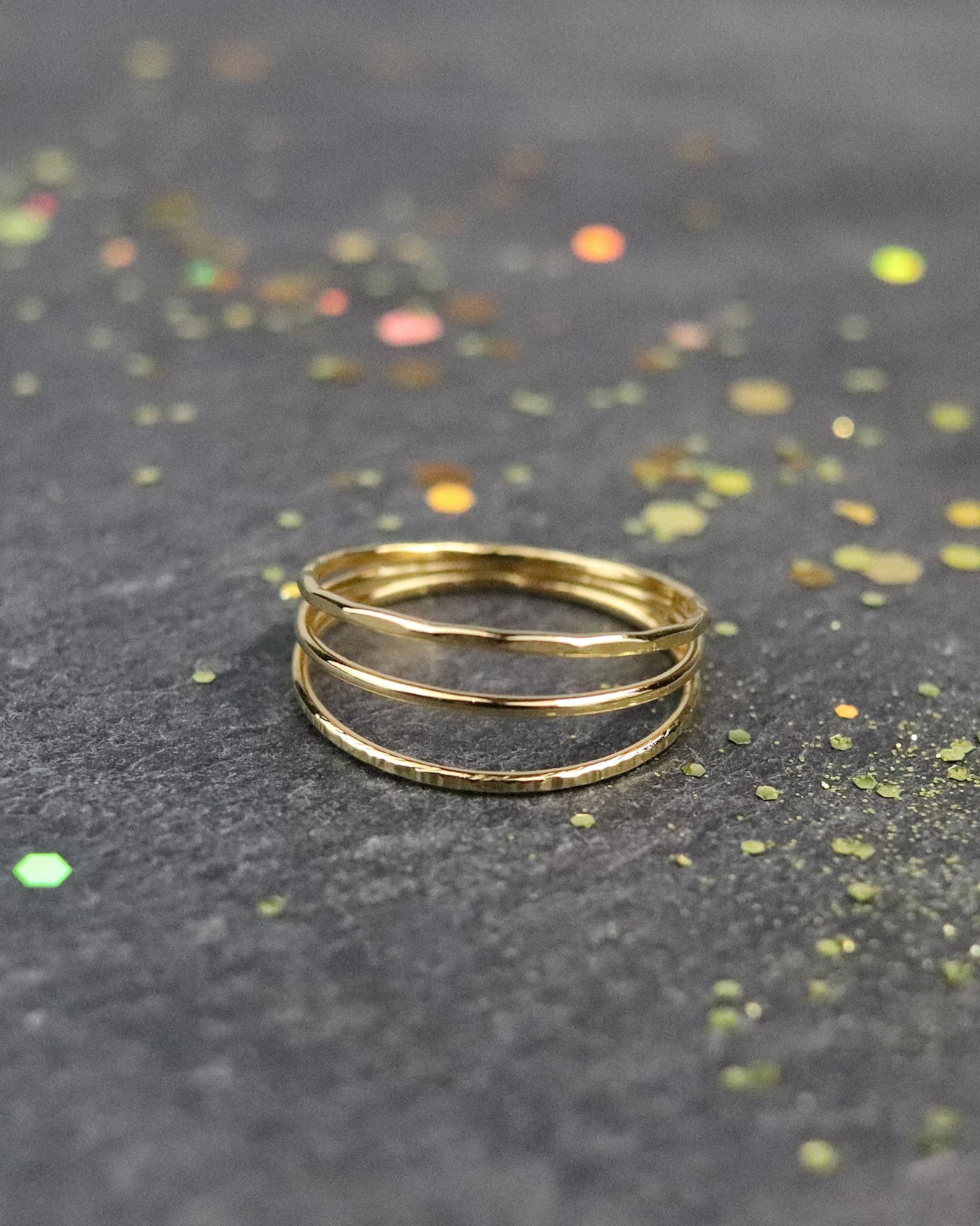 Bague Trio trois anneaux, un lisse, un martelée et un ciselé soudés en une seule bague en vermeil (argent plaqué or 5 microns) sur fond ardoise vue de face