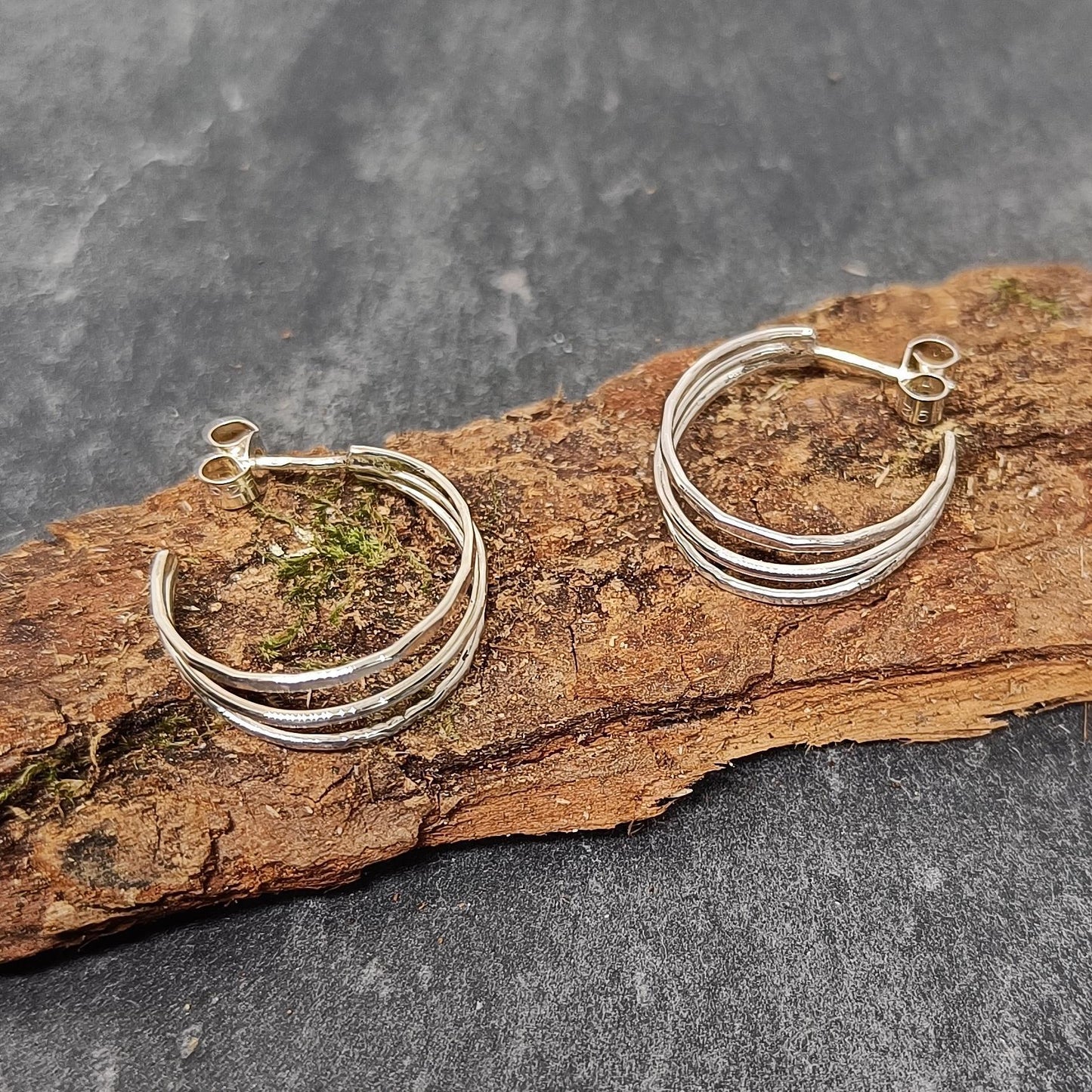 bijoux marion chappaz en argent 925 boucles d'oreilles pour femme créoles trio trois anneaux lisse martelé et ciselé posées sur fond bois