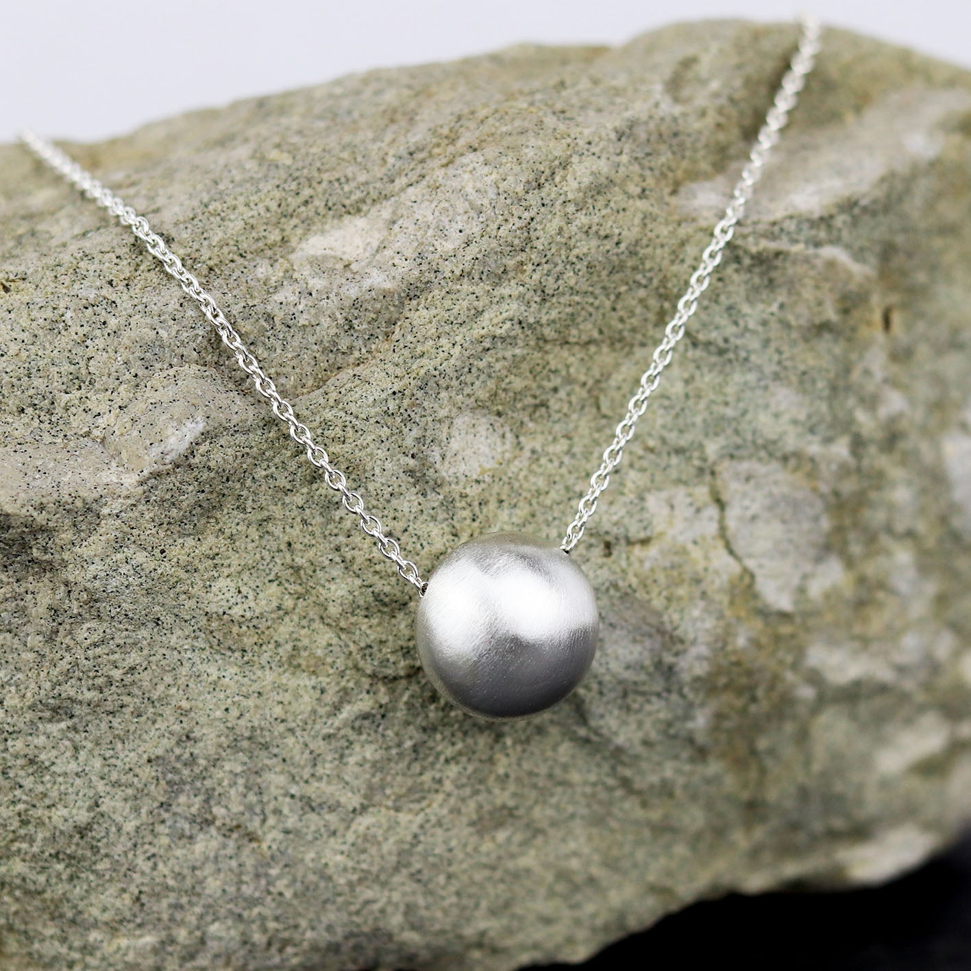 bijoux marion chappaz collier argent bulle sphere pour femme posé sur une pierre chaine maille forçat