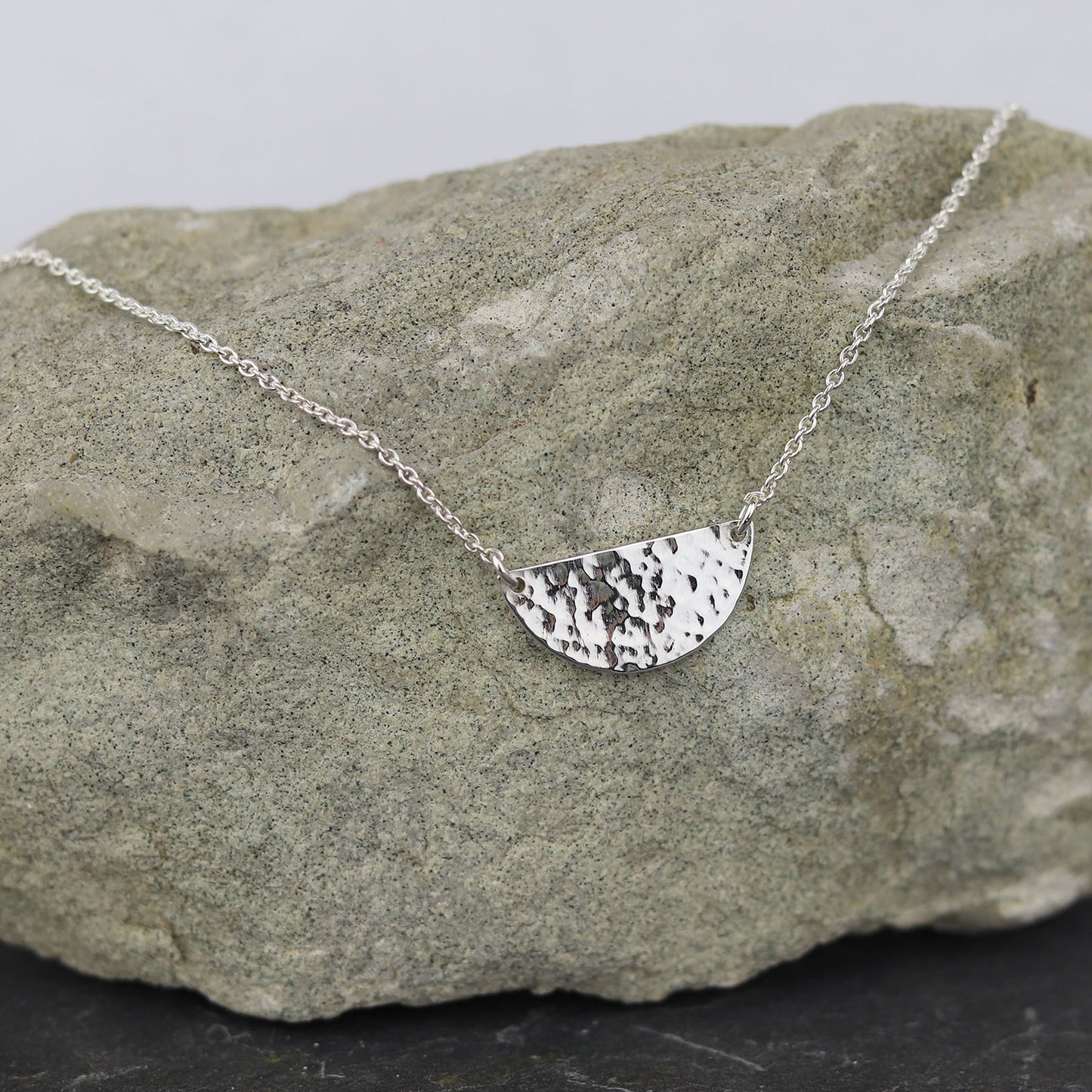 bijoux marion chappaz collier argent 925 demi médaille martelée pour femme posé sur une pierre