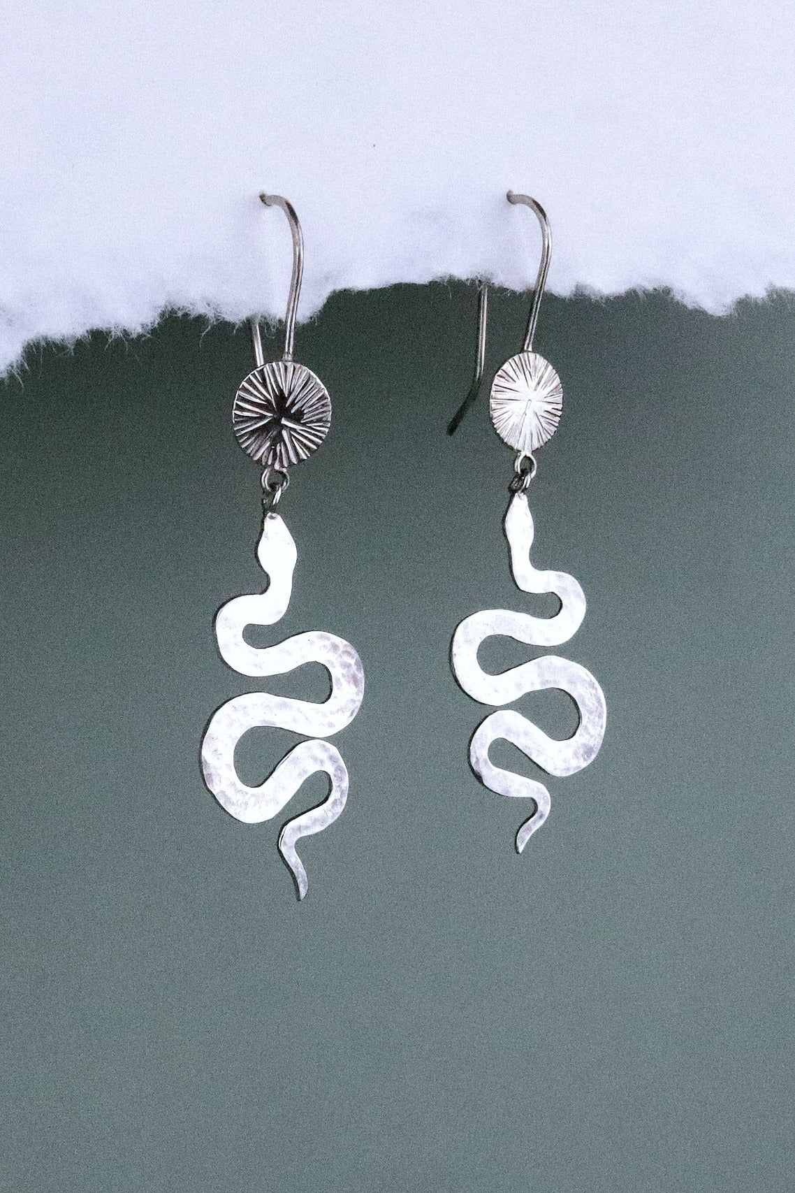 Bijoux Marion Chappaz boucles d'oreilles dormeuses serpent et soleil en argent 925/1000 suspendues sur fond blanc et vert