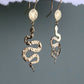 Bijoux Marion Chappaz boucles d'oreilles dormeuses serpent et soleil en vermeil (argent plaqué or) suspendues sur fond blanc et vert